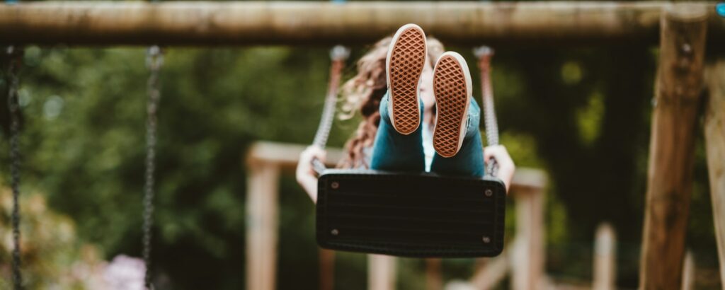 woman riding swing near trees