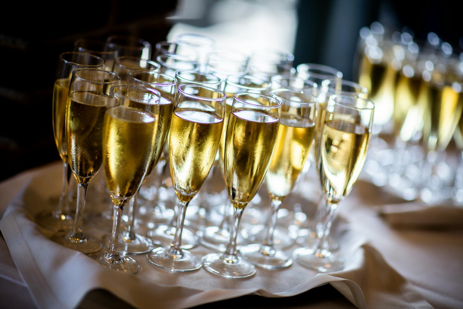 Multiple champagne glasses filled with sparkling wine at an event. Perfect for celebrations and parties.