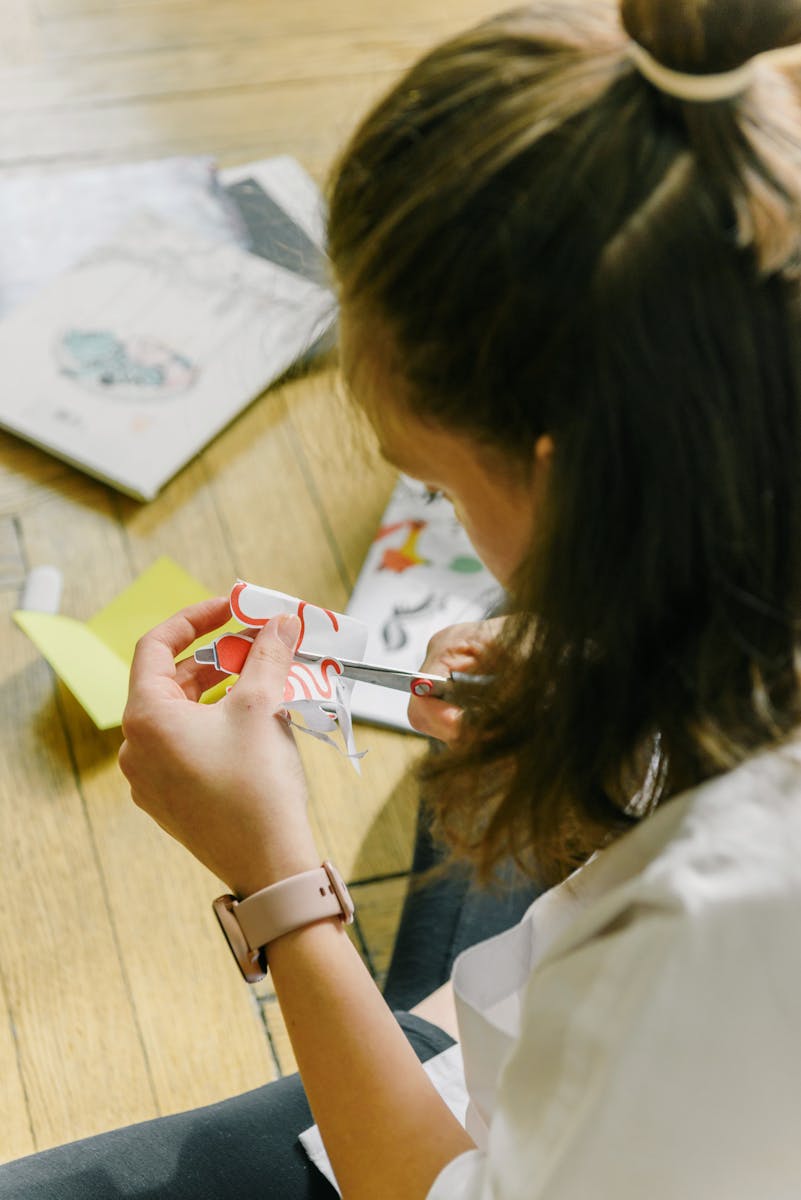 Close-up of a person cutting colorful paper indoors, showcasing a creative project.